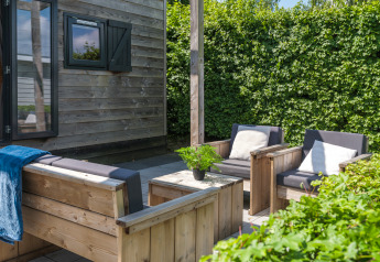 Udendørs terrasse ved Tiny House på Holiday Park Mölke i Holland med træmøbler og grøn omgivelse.