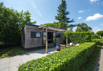 Tiny House in Holiday Park Mölke, Nederland, houten woning met terras en tuinmeubelen tussen het groen.