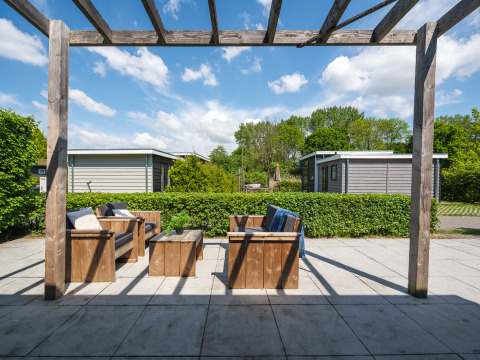 Coin salon extérieur en bois du Tiny House au Holiday Park Mölke, Pays-Bas, sous une pergola.
