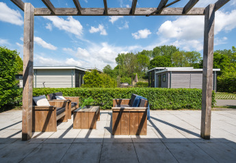 Outdoor seating area with wooden furniture at Tiny House, Holiday Park Mölke, Netherlands, under pergola.
