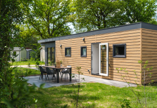 Moderne Tiny Cabin met houten buitenkant en terras in Holiday Park Mölke, Nederland, omgeven door natuur.