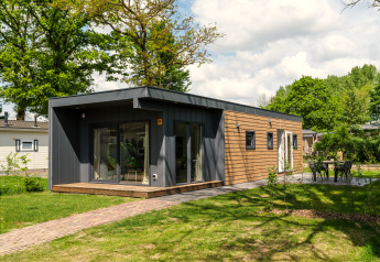 Moderne tiny cabin ved Holiday Park Mölke i Holland, omgivet af grønne træer og en velplejet have.