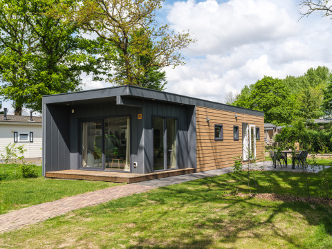 Modernes Tiny Cabin im Holiday Park Mölke in den Niederlanden, umgeben von Grün und Bäumen.