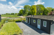 Moderne bungalow med terrasse og udsigt over natur ved Holiday Park Mölke, Nederlandene, på en solrig dag.