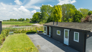 Moderne bungalow met terras en uitzicht op de natuur bij Holiday Park Mölke, Nederland, op een zonnige dag.