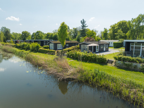 Bungalow sulla Regge al Holiday Park Mölke, Paesi Bassi, immersi nel verde accanto all’acqua.