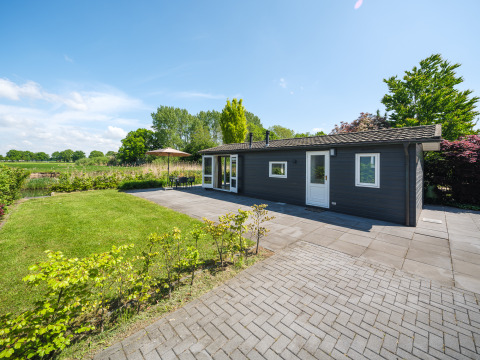 Bungalow aan de Regge bij Holiday Park Mölke in Nederland, met tuin, terras en stralende blauwe lucht.