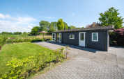 Bungalow aan de Regge bij Holiday Park Mölke in Nederland, met tuin, terras en heldere blauwe lucht.
