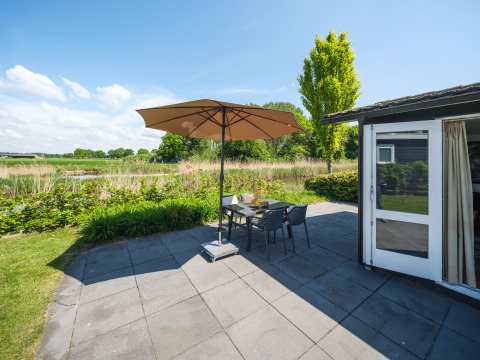 Zonnig terras met parasol bij een bungalow aan de Regge, Holiday Park Mölke, Nederland