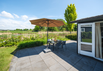 Patio soleggiato con ombrellone e tavolo al Bungalow at the Regge, Holiday Park Mölke, Paesi Bassi