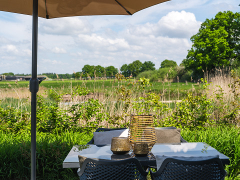Terraszicht van Bungalow aan de Regge bij Holiday Park Mölke, met tafel, stoelen en groen uitzicht.