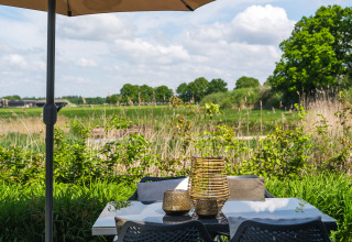 Terraszicht van Bungalow aan de Regge bij Holiday Park Mölke, met tafel, stoelen en groen uitzicht.
