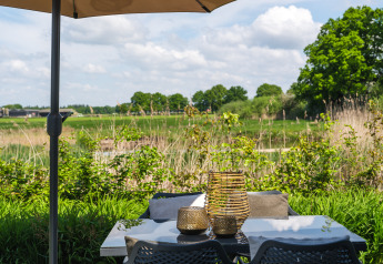 Terraszicht van Bungalow aan de Regge bij Holiday Park Mölke, met tafel, stoelen en groen uitzicht.