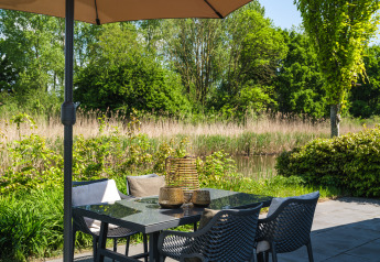 Area salotto esterna con tavolo e sedie al bungalow sul Regge, Holiday Park Mölke, Paesi Bassi.