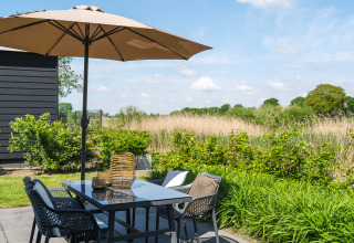 Buiten eethoek met parasol en uitzicht op velden bij Bungalow at the Regge, Holiday Park Mölke, Nederland.