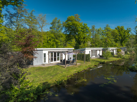 Lodge Mistique presso Holiday Park De Lochemse Berg, Paesi Bassi, moderni lodge accanto a un canale.