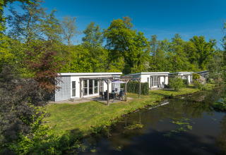 Lodge Mistique presso Holiday Park De Lochemse Berg, Paesi Bassi, moderni lodge accanto a un canale.