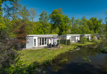 Lodge Mistique presso Holiday Park De Lochemse Berg, Paesi Bassi, moderni lodge accanto a un canale.