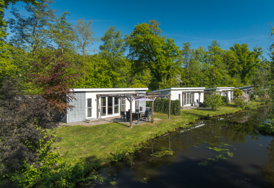 Lodge Mistique presso Holiday Park De Lochemse Berg, Paesi Bassi, moderni lodge accanto a un canale.