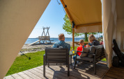 Familie entspannt sich auf der Terrasse eines Safarizelts am Strand bei Zuiderzee, Niederlande, bei Sonne.