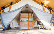 Ingang van luxe glampingtent aan het strand bij Zuiderzee, Nederland, met keuken en eetgedeelte.