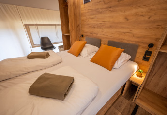 Camera da letto del Glampingtent Beachfront Luxe a Zuiderzee, Paesi Bassi, con letto matrimoniale e arredi in legno.