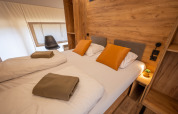 Schlafzimmer im Glampingtent Beachfront Luxe am Zuiderzee in den Niederlanden mit Doppelbett und Holzwand.