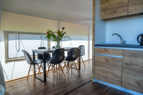 Interior of Glampingtent Beachfront Luxe at Zuiderzee, Netherlands, dining table, kitchen, and flowers.