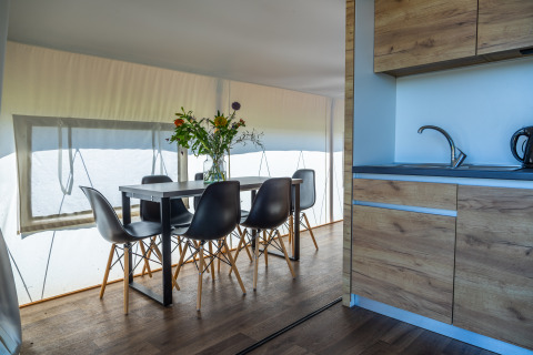 Interno del Glampingtent Beachfront Luxe a Zuiderzee, Paesi Bassi, tavolo da pranzo, cucina e fiori.