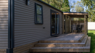 Vista exterior de la cabaña Vakantiehuis Familie (PL.82) con terraza de madera y zona de estar cubierta.