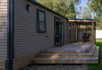 Außenansicht der Vakantiehuis Familie (PL.82) Lodge mit Holzterrasse und überdachtem Essbereich.