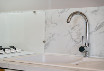 Moderne Küchenspüle mit Wasserhahn und Marmorhintergrund in Vakantiehuis Familie bei Camping Papillon.