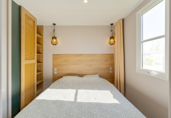 Schlafzimmer im Vakantiehuis Familie, Camping Papillon, mit Doppelbett, Fenster und stilvollem Licht.