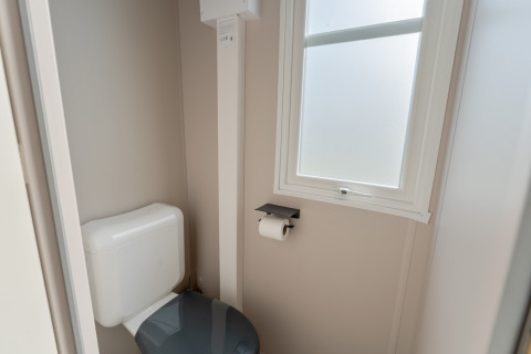 Lichte wc met toilet, toiletrolhouder en raam in Vakantiehuis Familie (PL.82) bij Camping Papillon.