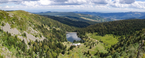 Vista panoramica su montagne, foreste e lago vicino a Gerbépal, Grand Est, Francia, sotto cielo nuvoloso.