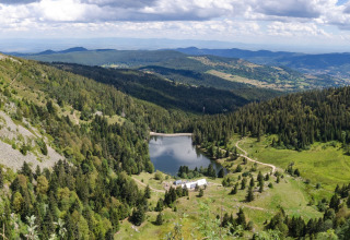 Vista panoramica su montagne, foreste e lago vicino a Gerbépal, Grand Est, Francia, sotto cielo nuvoloso.