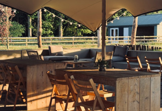 Area salotto esterna con tavoli e sedie in legno sotto tendone al parco vacanze Thuysgrond, Brabante Settentrionale, Paesi Bassi.