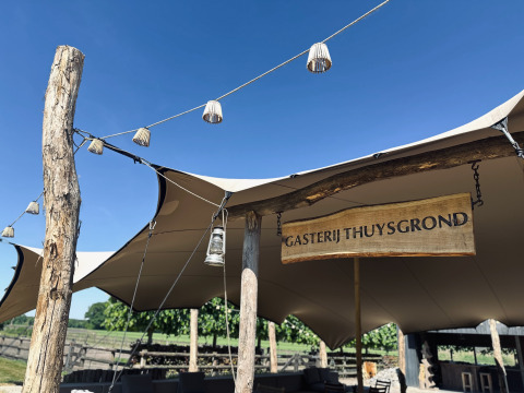 Struttura esterna con tenda e insegna in legno 'Gasterij Thuysgrond' in un parco vacanze nel North-Brabant, Paesi Bassi.