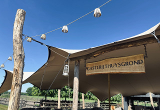 Struttura esterna con tenda e insegna in legno 'Gasterij Thuysgrond' in un parco vacanze nel North-Brabant, Paesi Bassi.