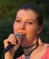 En kvinde synger i en mikrofon på Thuysgrond feriepark i Nord-Brabant, Nederlandene, under åben himmel.