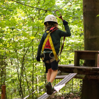 Barn med hjelm og sele balancerer på en reb-bane i en grøn skov nær Bergeijk, Nord-Brabant, Holland.