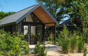 Summer Lodge en el parque recreativo y puerto deportivo Rhederlaagse Meren en los Países Bajos, rodeado de vegetación.