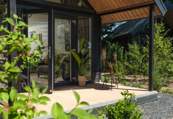 Lodge d’été moderne avec portes vitrées et terrasse en bois, entouré de verdure à Rhederlaagse Meren, Pays-Bas.