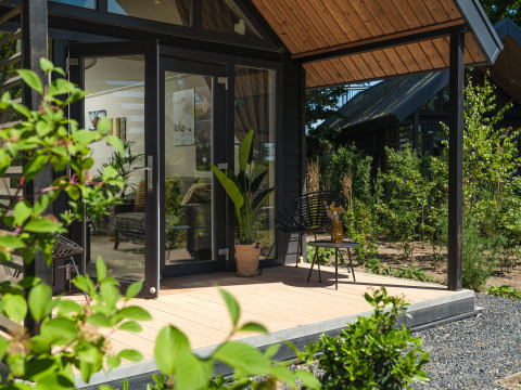 Lodge de verano moderno con puertas de cristal y terraza de madera rodeado de vegetación en Rhederlaagse Meren.