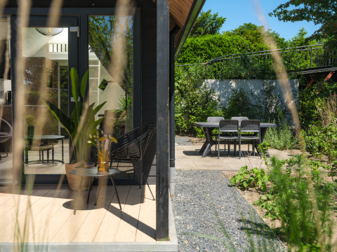 Terrasse der Summer Lodge im Freien mit Sitzmöglichkeiten und Blick auf Garten bei Rhederlaagse Meren, Niederlande.