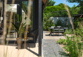 Terrasse der Summer Lodge im Freien mit Sitzmöglichkeiten und Blick auf Garten bei Rhederlaagse Meren, Niederlande.