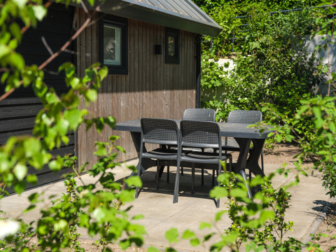 Zona de comedor exterior en Summer Lodge, parque recreativo y Marina Rhederlaagse Meren, Países Bajos, rodeada de vegetación.
