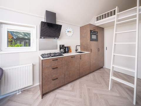 Moderne tekøkken med stige til hems i Summer Lodge ved Rhederlaagse Meren, Holland, lyst og kompakt.
