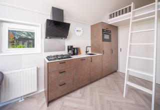 Moderne kitchenette met trap naar mezzanine in Summer Lodge bij Rhederlaagse Meren, Nederland.