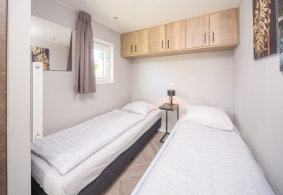 Lichte kamer in Summer Lodge met twee enkele bedden, raam, houten kasten en kunst aan de muur.